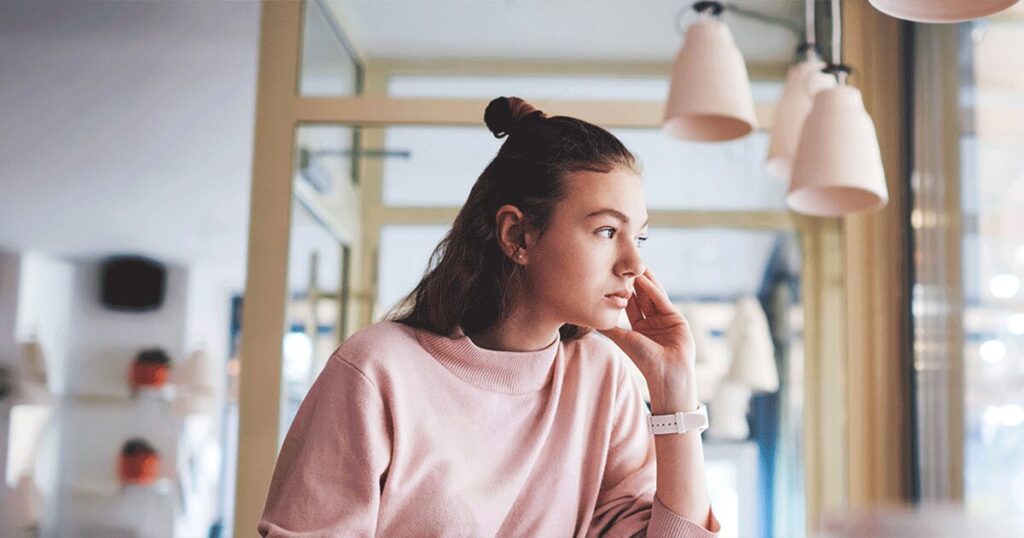 Young woman sitting alone and thinking about a possible pregnancy