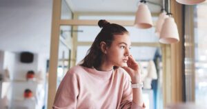 Young woman sitting alone and thinking about a possible pregnancy
